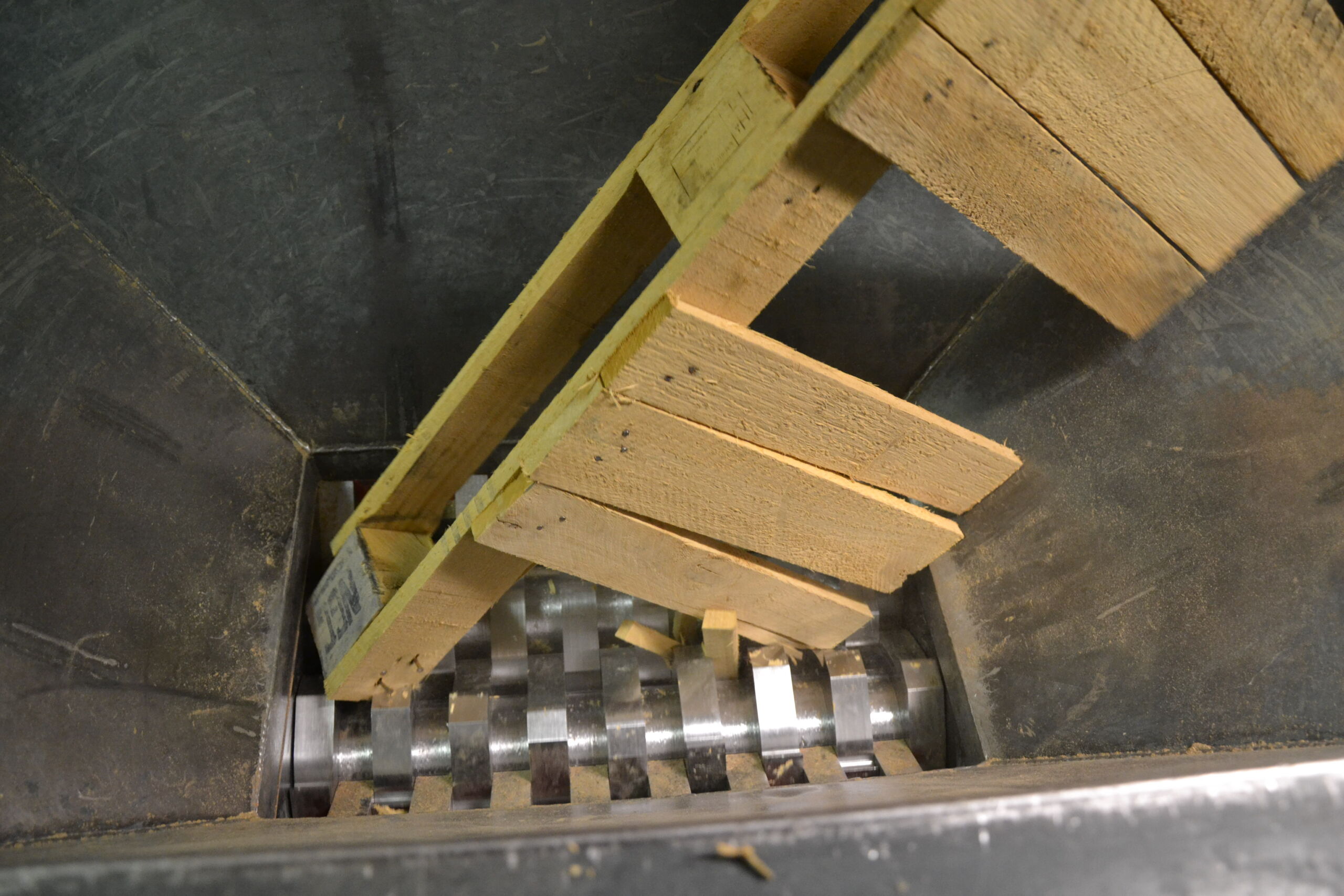 Wooden pallet entering an industrial shredder